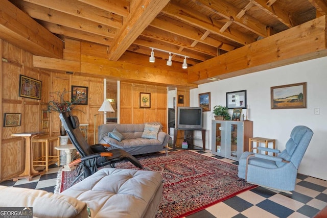 living room featuring track lighting, wood walls, beamed ceiling, and tile patterned floors