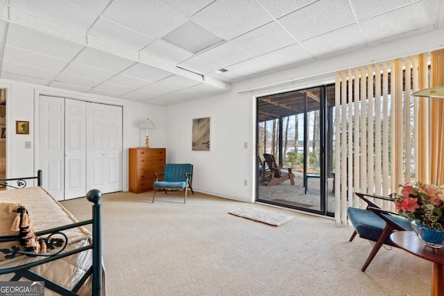 interior space featuring access to exterior, a closet, a drop ceiling, and carpet floors