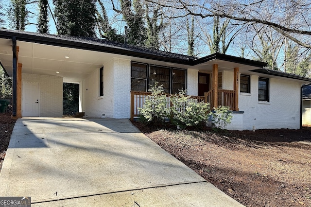 view of front of house with brick siding, an attached carport, a porch, crawl space, and driveway