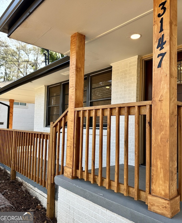 entrance to property with brick siding and a porch