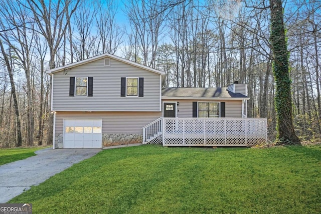 split level home with a chimney, concrete driveway, an attached garage, a front yard, and stone siding