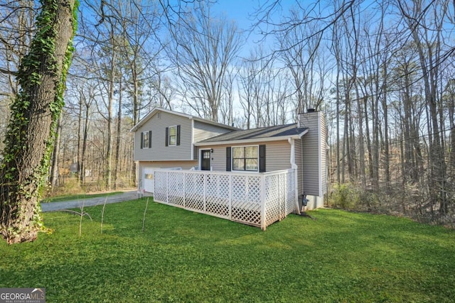 view of side of home featuring a garage, aphalt driveway, a lawn, and a chimney