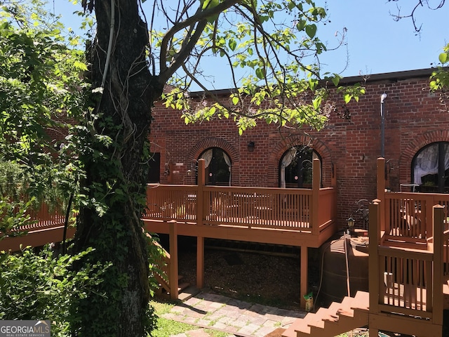 back of property featuring brick siding and a wooden deck