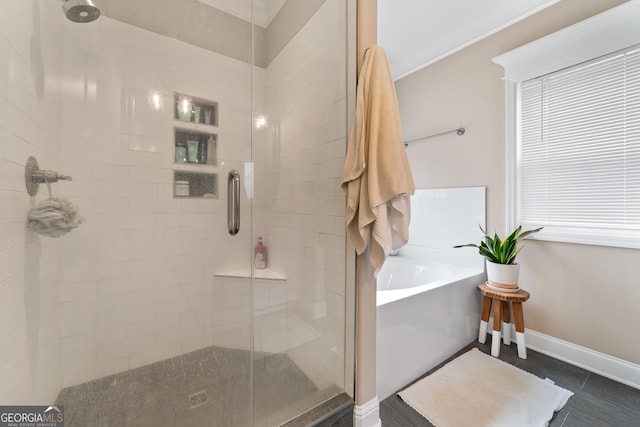 full bath with ornamental molding, a garden tub, a shower stall, and baseboards