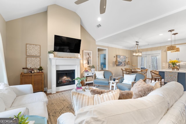 living area featuring light wood finished floors, visible vents, a ceiling fan, ornamental molding, and a warm lit fireplace