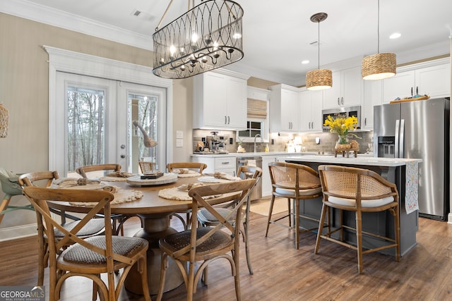 dining room with wood finished floors, crown molding, and french doors