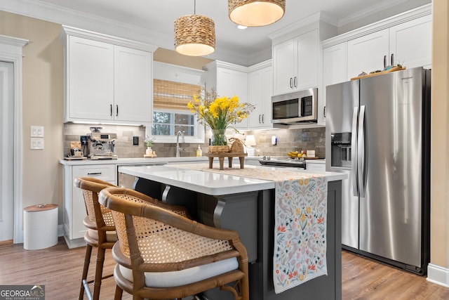 kitchen featuring light wood-style flooring, a sink, white cabinetry, appliances with stainless steel finishes, and tasteful backsplash