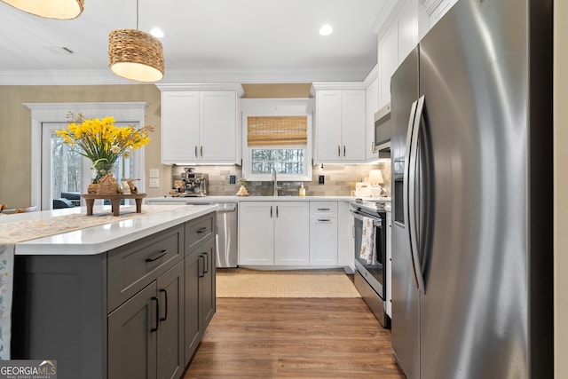 kitchen with crown molding, stainless steel appliances, light countertops, gray cabinetry, and a sink