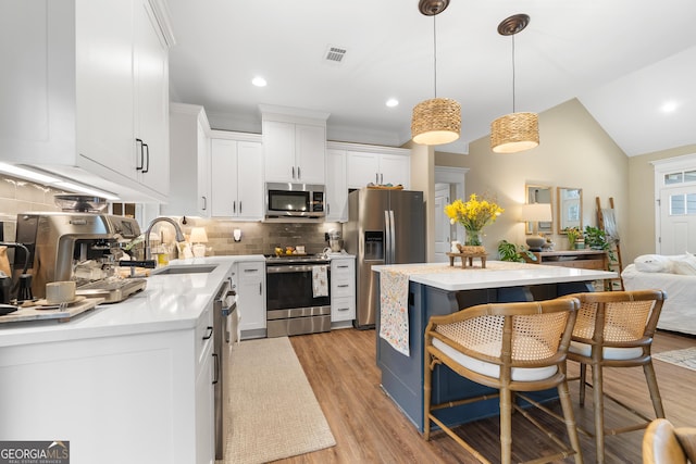 kitchen with visible vents, light countertops, appliances with stainless steel finishes, a center island, and tasteful backsplash