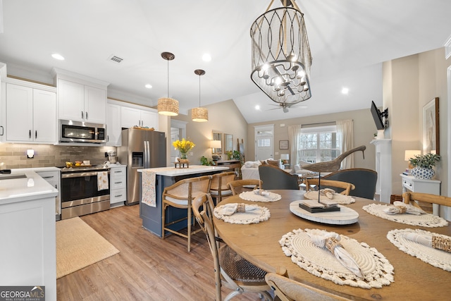 dining room with a notable chandelier, lofted ceiling, recessed lighting, visible vents, and light wood-type flooring