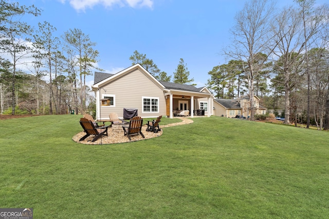 rear view of property featuring an outdoor fire pit, ceiling fan, a patio, and a lawn