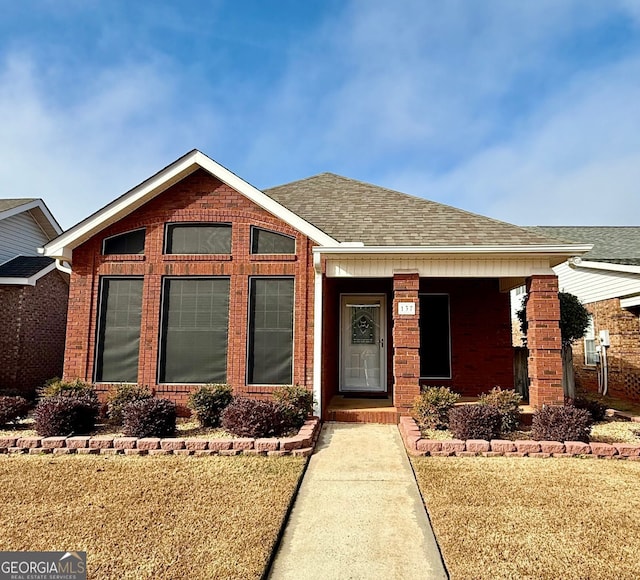 view of front of house with brick siding and roof with shingles