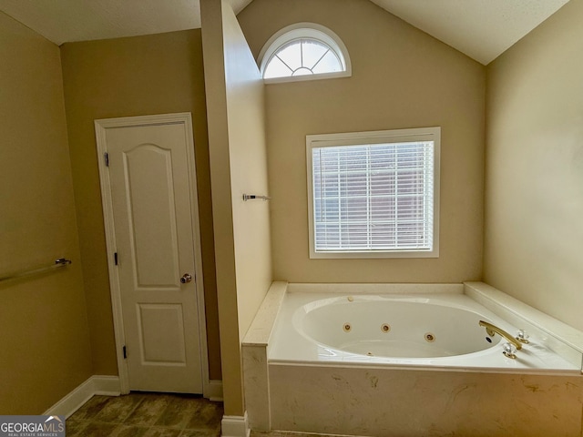 full bath with a tub with jets and vaulted ceiling