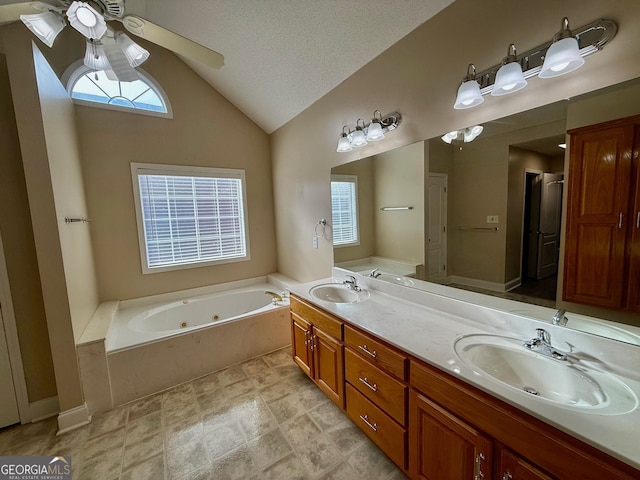 bathroom featuring double vanity, vaulted ceiling, a sink, a textured ceiling, and a jetted tub