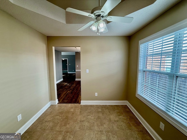 empty room with a ceiling fan and baseboards