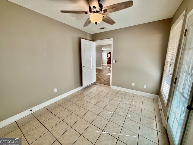 unfurnished bedroom with visible vents, light tile patterned flooring, ceiling fan, a textured ceiling, and baseboards