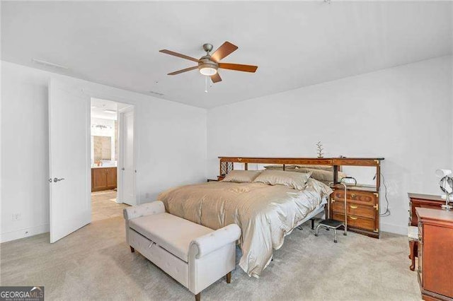 bedroom with connected bathroom, light colored carpet, and ceiling fan