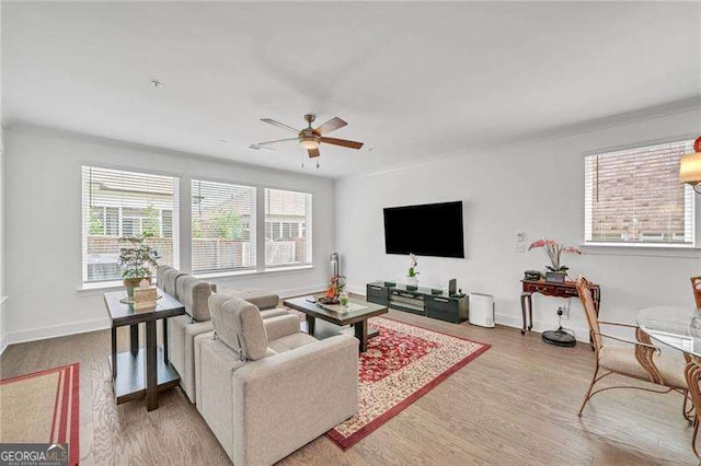 living room with ceiling fan, baseboards, and wood finished floors