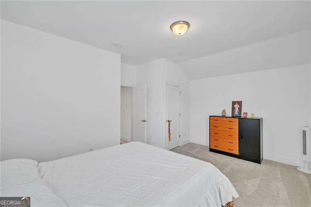 bedroom with light colored carpet, vaulted ceiling, and baseboards