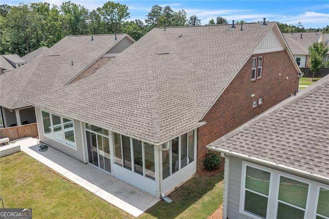 rear view of house featuring a patio, a shingled roof, a lawn, a sunroom, and fence