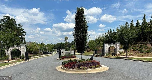 view of street featuring curbs, sidewalks, and a gate