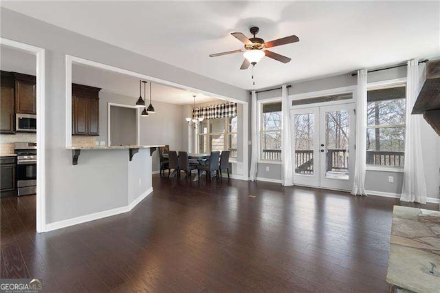 living area with dark wood-style floors, baseboards, and ceiling fan with notable chandelier