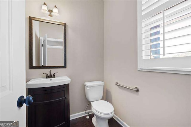 bathroom with toilet, baseboards, wood finished floors, and vanity