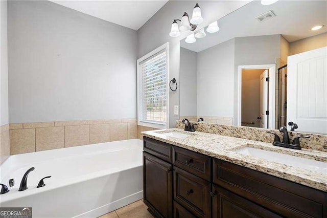 bathroom with tile patterned flooring, visible vents, a sink, and a garden tub