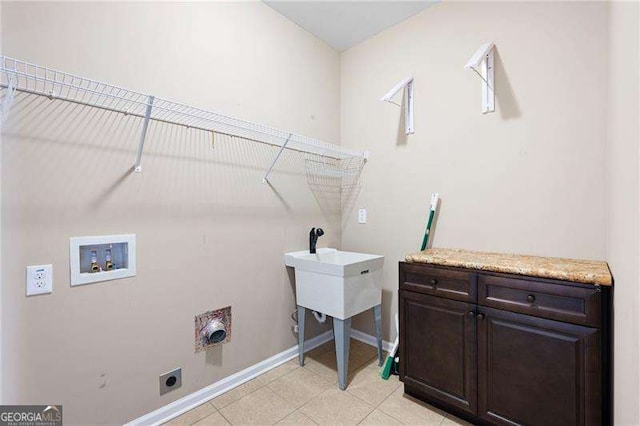 clothes washing area with light tile patterned floors, hookup for a washing machine, hookup for an electric dryer, baseboards, and cabinet space