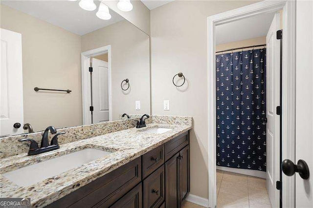 bathroom with double vanity, a sink, baseboards, and tile patterned floors