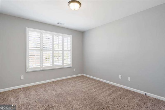 carpeted spare room featuring visible vents and baseboards