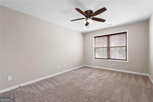 carpeted spare room featuring a ceiling fan and baseboards