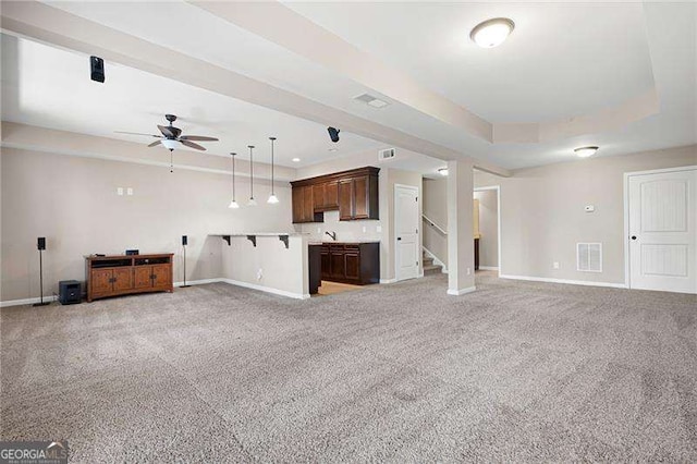 unfurnished living room featuring light carpet, stairway, baseboards, and a tray ceiling