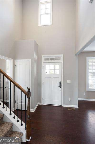 entrance foyer with a high ceiling, stairway, wood finished floors, and baseboards