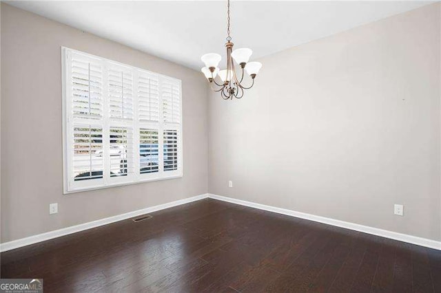 unfurnished room with a notable chandelier, wood finished floors, visible vents, and baseboards