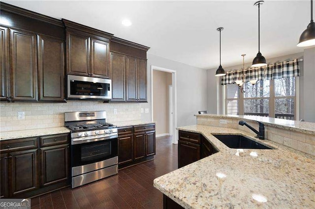 kitchen featuring appliances with stainless steel finishes, a sink, backsplash, and light stone countertops