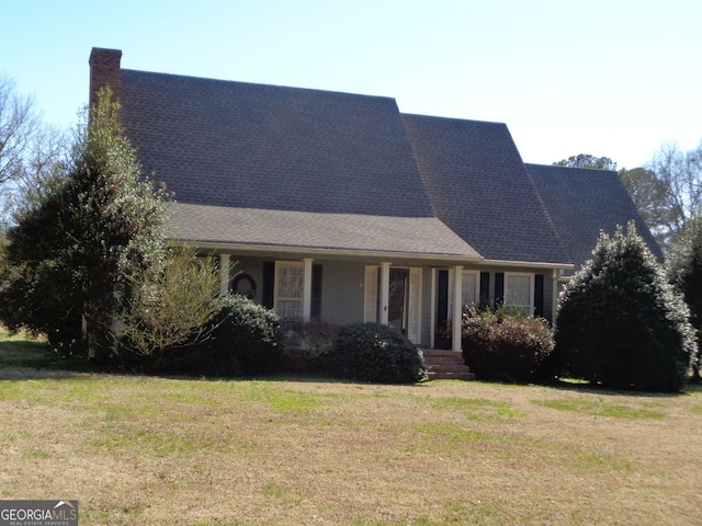 view of front of property with a front yard, roof with shingles, and a chimney