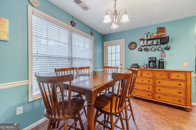 dining area featuring visible vents, baseboards, light tile patterned floors, an inviting chandelier, and a textured ceiling