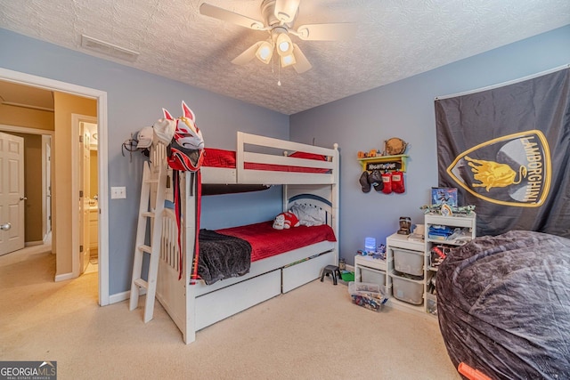 carpeted bedroom featuring ceiling fan, visible vents, and a textured ceiling