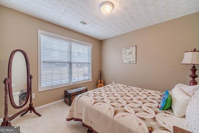 bedroom featuring visible vents, light colored carpet, a textured ceiling, and baseboards