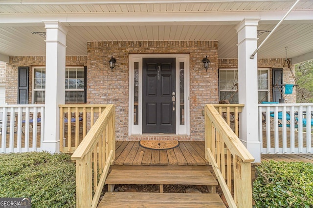 property entrance featuring a porch and brick siding