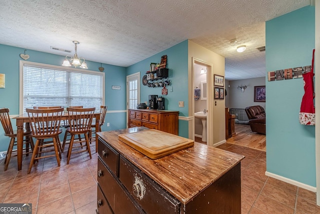 kitchen featuring light tile patterned flooring, visible vents, a textured ceiling, and a notable chandelier