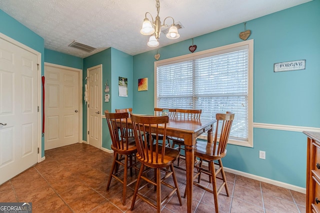 tiled dining room with a notable chandelier, baseboards, visible vents, and a textured ceiling