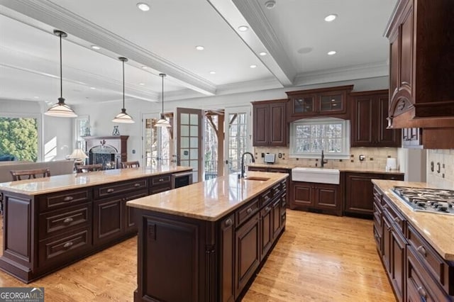 230 Hawks Lake Dr, Ball Ground, GA 30107 - kitchen featuring a center island with sink, stainless steel gas stovetop, decorative backsplash, light wood-style flooring, and a fireplace