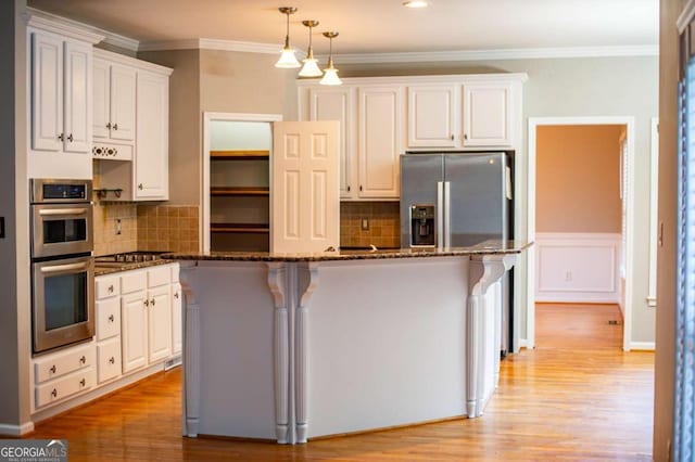 kitchen featuring light wood-style flooring, white cabinetry, dark stone counters, appliances with stainless steel finishes, and crown molding