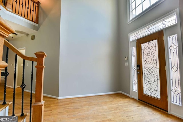 entrance foyer with stairway, baseboards, a high ceiling, and wood finished floors