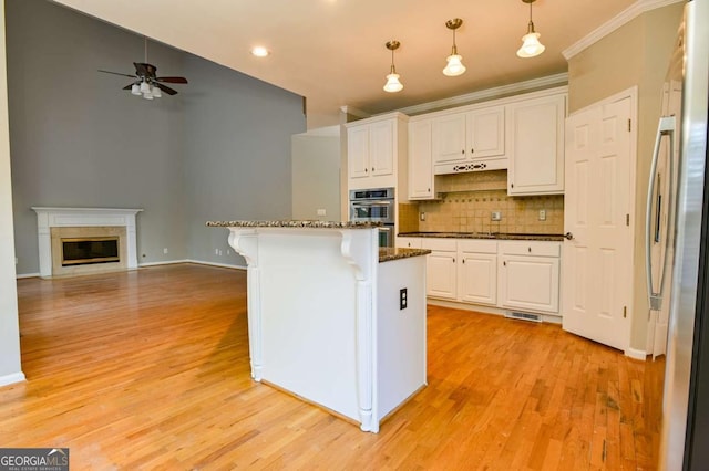 kitchen with a breakfast bar area, appliances with stainless steel finishes, white cabinets, and a high end fireplace