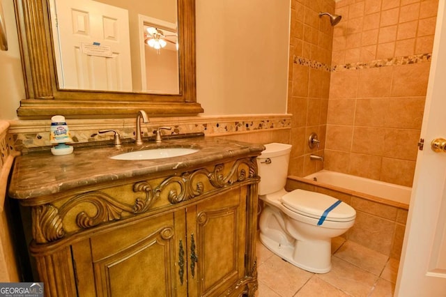 full bath featuring tile patterned floors, tiled shower / bath, toilet, wainscoting, and vanity