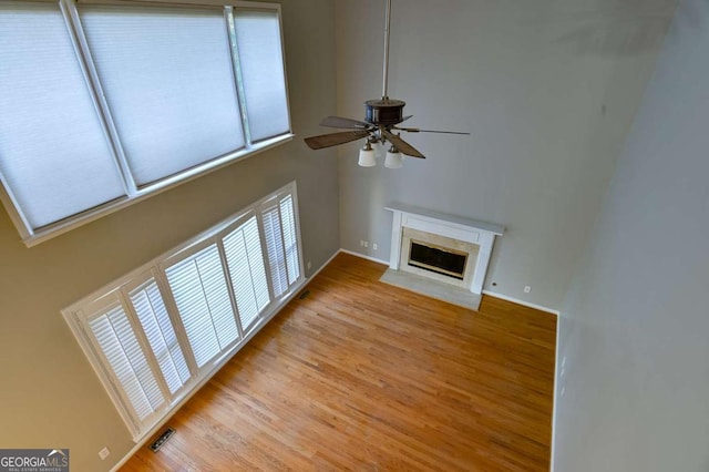 unfurnished living room with a high end fireplace, visible vents, light wood-style flooring, and ceiling fan