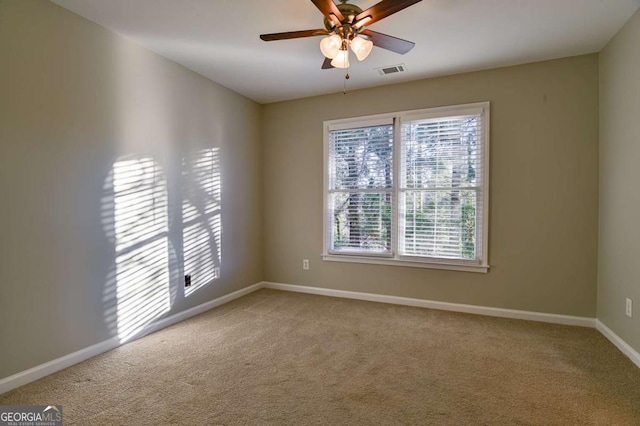 carpeted spare room featuring a ceiling fan, baseboards, and visible vents